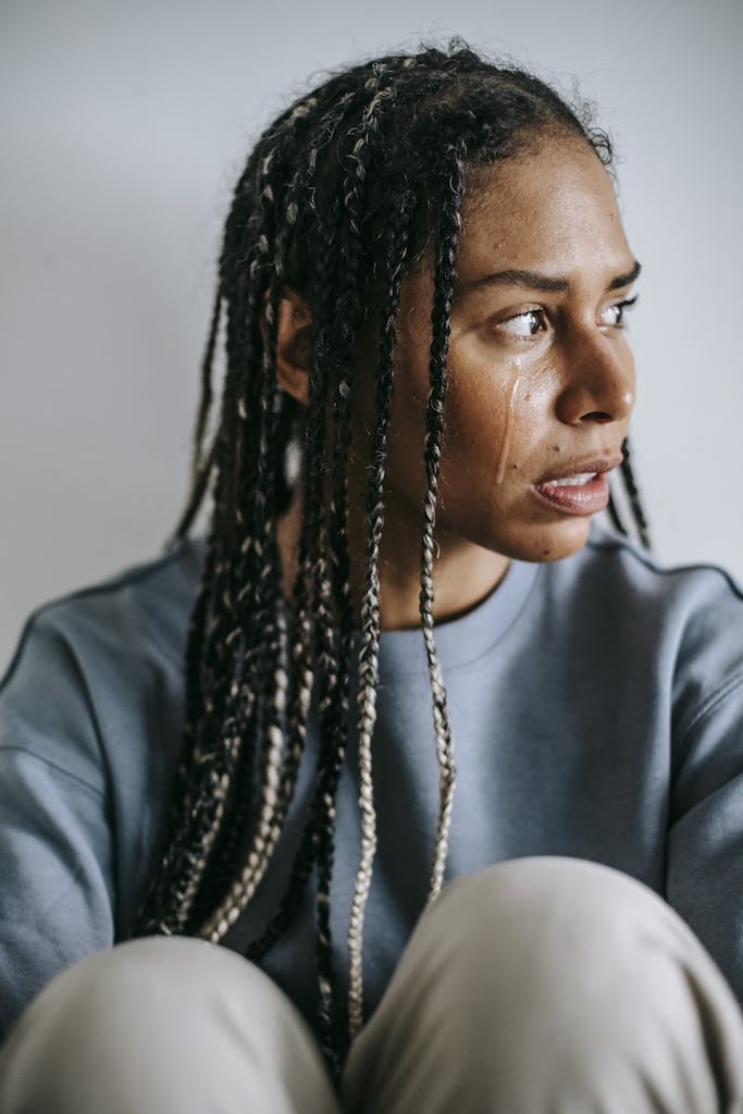 Sorrowful black woman crying in light room